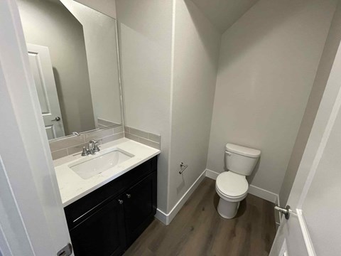 A white toilet sits in a bathroom next to a sink.