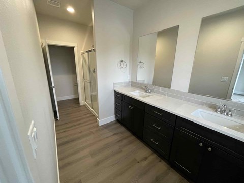 A bathroom with a sink, mirror, and wooden floors.