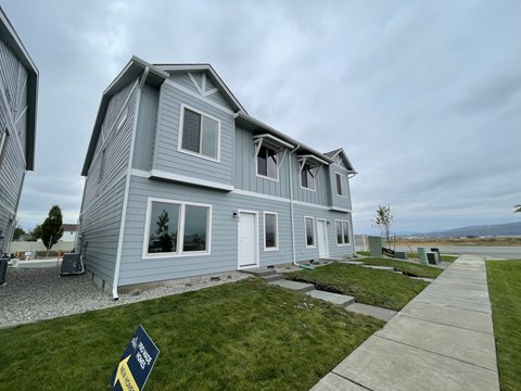 A house with a grey exterior and a sign in front of it.