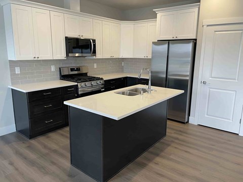 A kitchen with a black island and white cabinets.