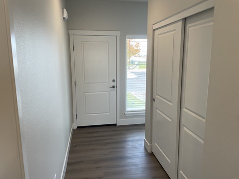 A white door is in a hallway with wood floors.