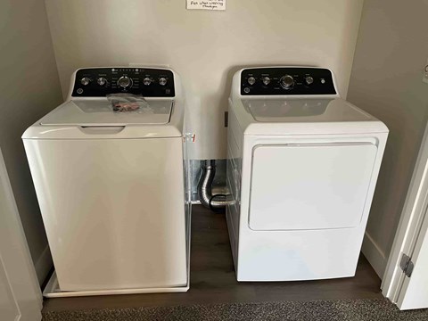 Two white front loading washing machines in a small room.