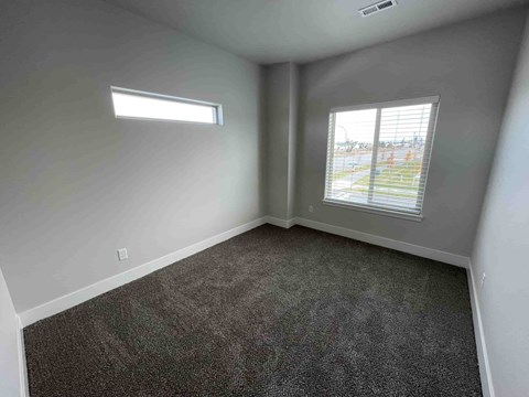 A room with a window and a carpeted floor.