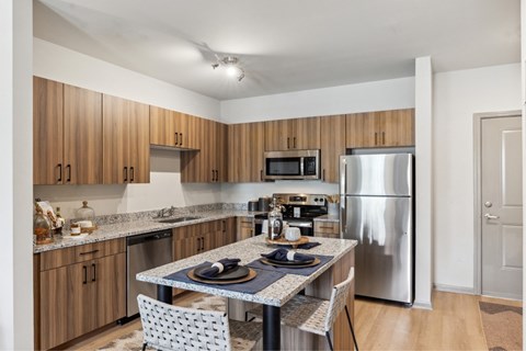 A kitchen with a table and chairs in front of a refrigerator.