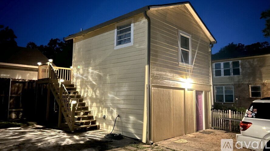 A house with a lit up front door and a car parked in the driveway.