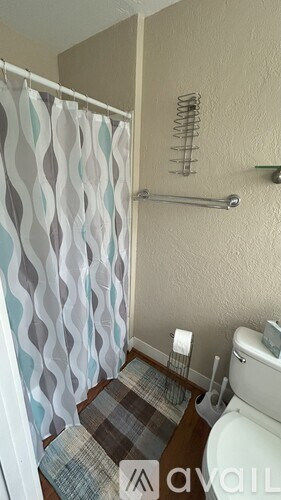 A bathroom with a toilet, a shower with a glass door, and a towel on the floor.