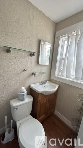 A white toilet with a toilet brush and a toilet paper holder.
