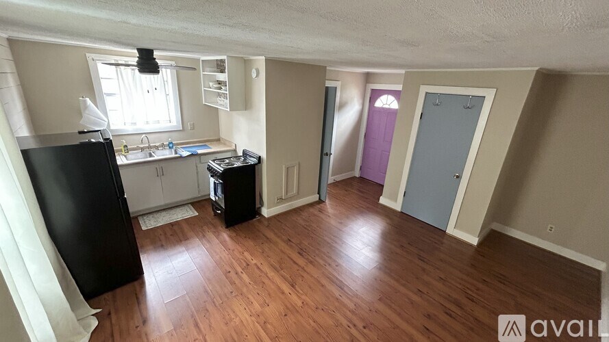 A room with wooden floors and a black refrigerator.
