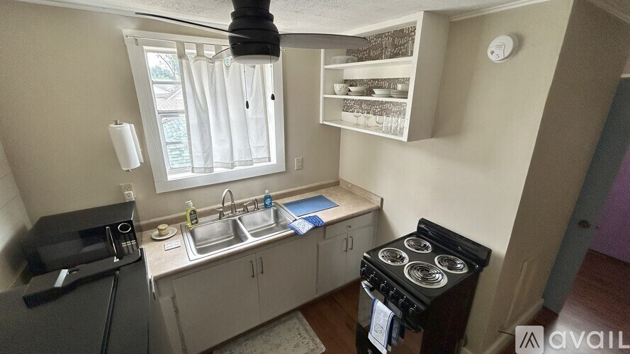 A kitchen with a black stove top oven and a white sink.
