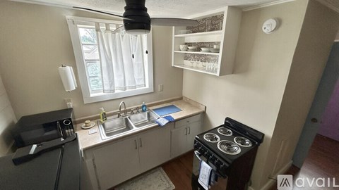 A kitchen with a black stove top oven and a white sink.