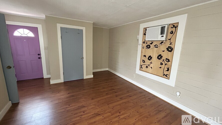 A room with a purple door and a wooden floor.