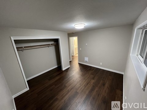 A room with a wooden floor and a white wall with a window.