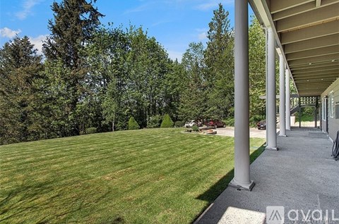 A house with a large lawn and trees in the background.