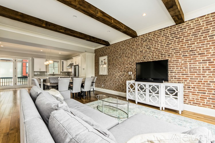 A living room with a grey couch and a brick wall.