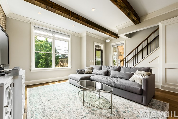 A living room with a grey couch and a glass coffee table.