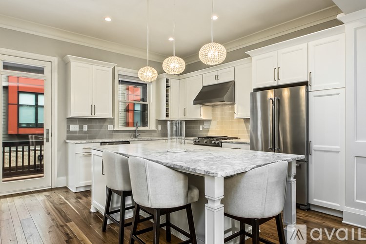 A kitchen with a marble table and white cabinets.