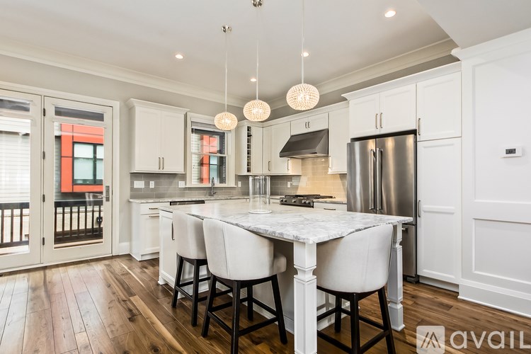 A modern kitchen with a large island and white chairs.