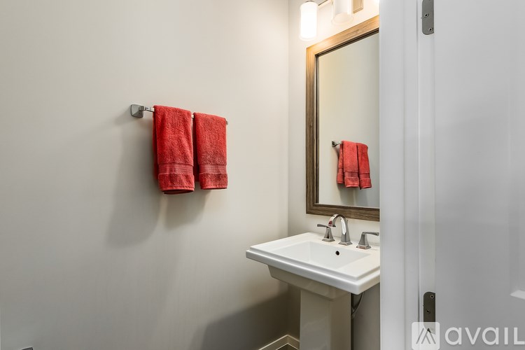 A bathroom with a white sink and red towels.