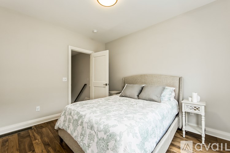 A bedroom with a bed, nightstand, and a doorway leading to another room.