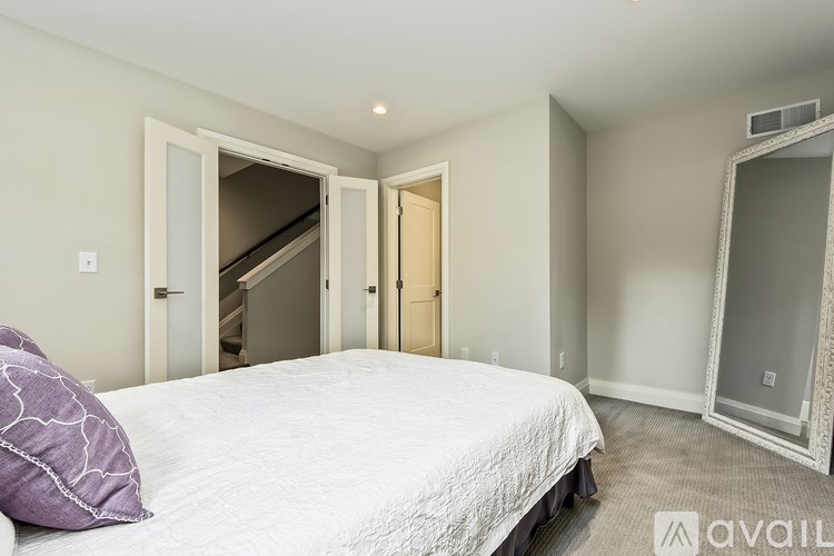 A bedroom with a bed, a mirror, and a staircase.
