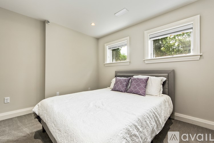 A bedroom with a large bed and two windows.