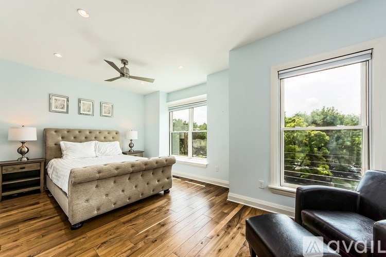 A bedroom with a large bed, a chair, and a window with a view of trees.