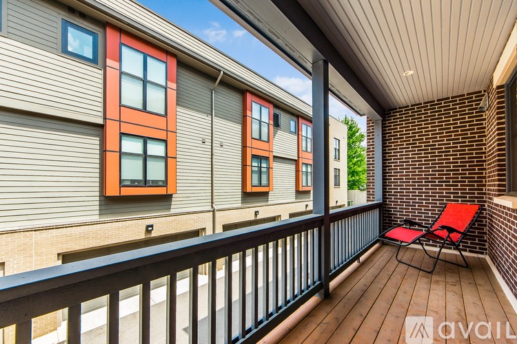 A balcony with a red chair and a black railing.
