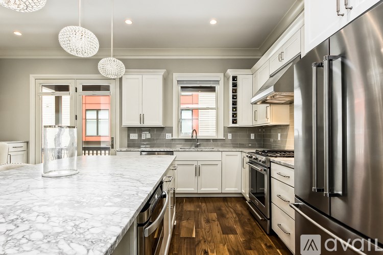 A modern kitchen with stainless steel appliances and white marble countertops.
