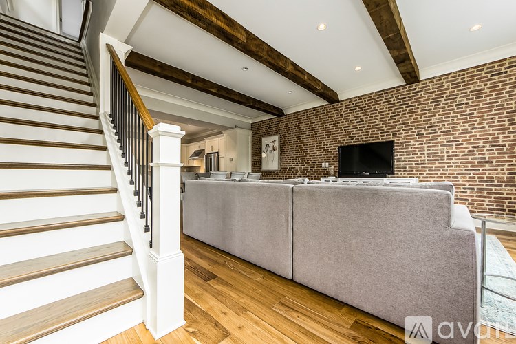 A living room with a grey couch and a staircase.