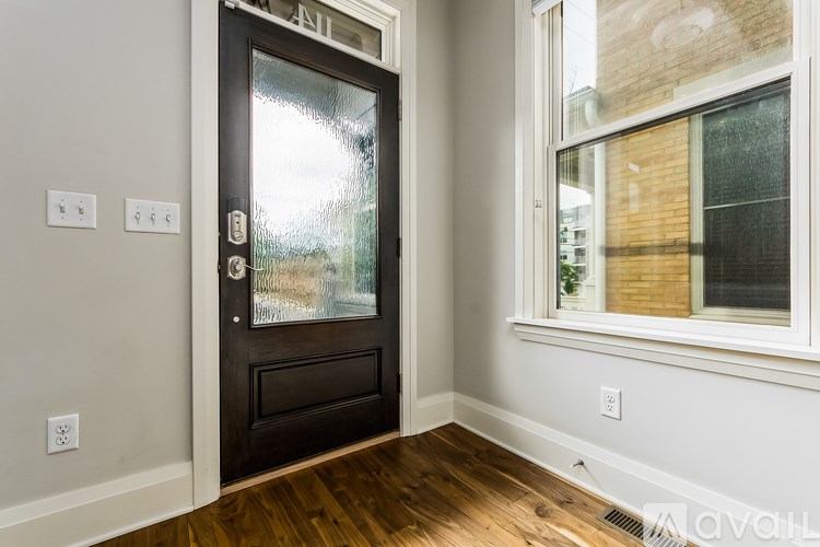 A black door with a glass window is in a room with white walls and a wooden floor.