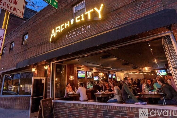 A group of people are sitting at tables outside of the Archetyp Tavern.