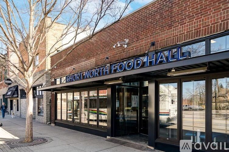 The front of a food hall with a tree in front.