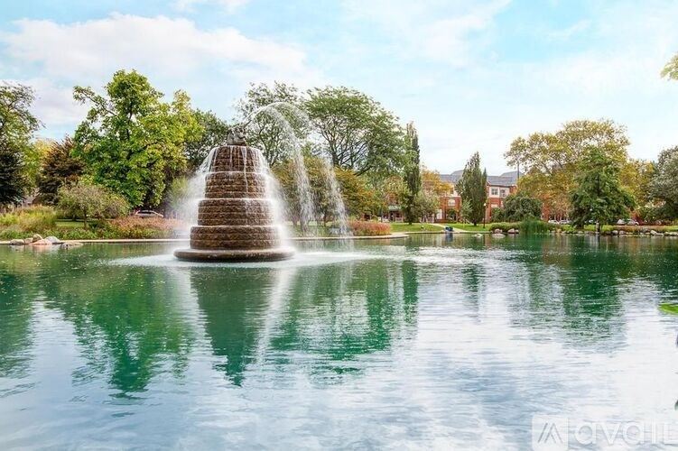 A fountain in the middle of a pond surrounded by trees.