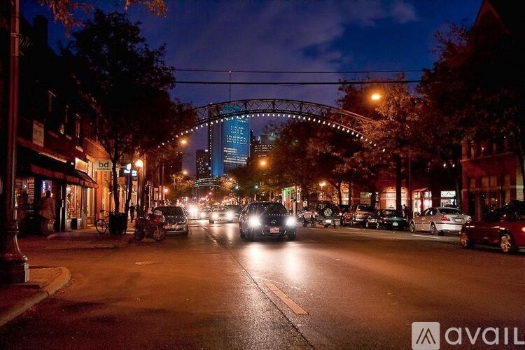 Cars driving on a street at night with a bridge in the background.
