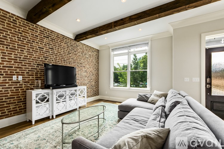 A living room with a grey couch and a black television on a white cabinet.