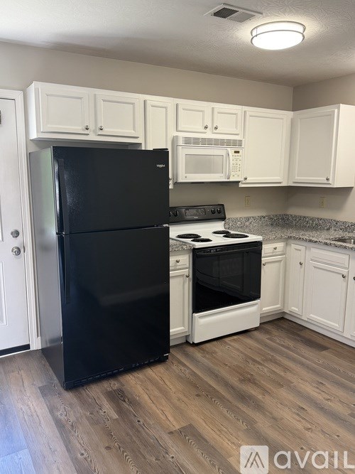 A kitchen with black fridge and white cabinets.