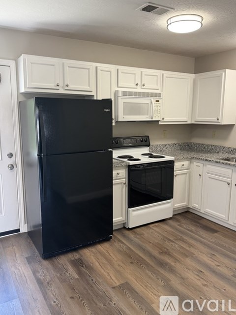 A kitchen with black fridge and white cabinets.