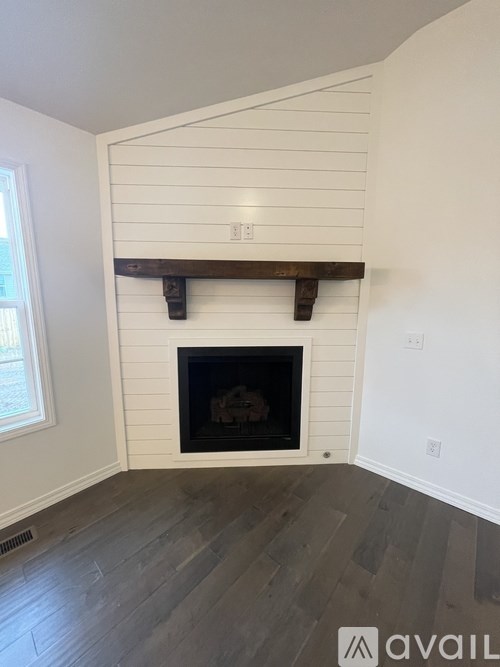 A fireplace with a white mantle and a wooden beam above it.