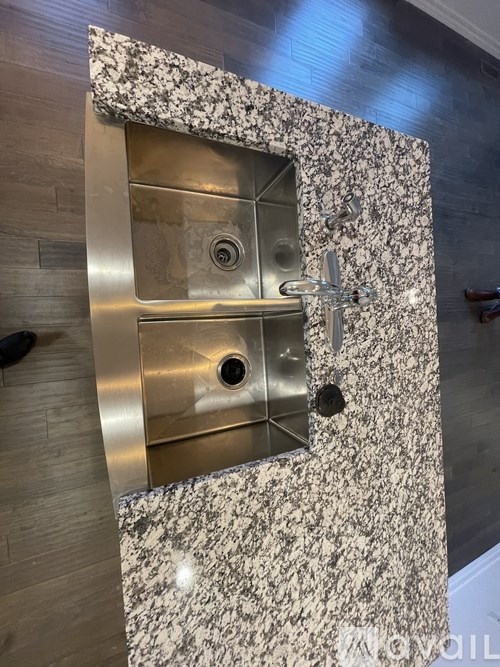 A bathroom sink with a granite countertop and a chrome faucet.
