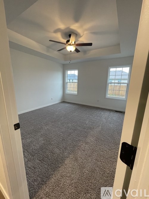 A room with a ceiling fan and carpeted floor.
