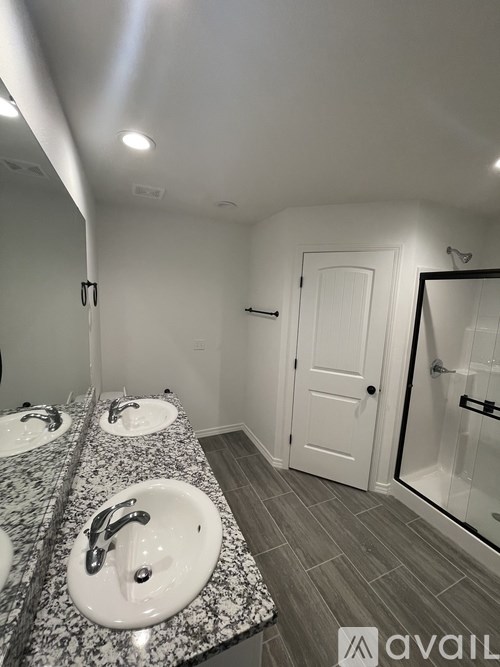 A bathroom with a granite countertop and two sinks.