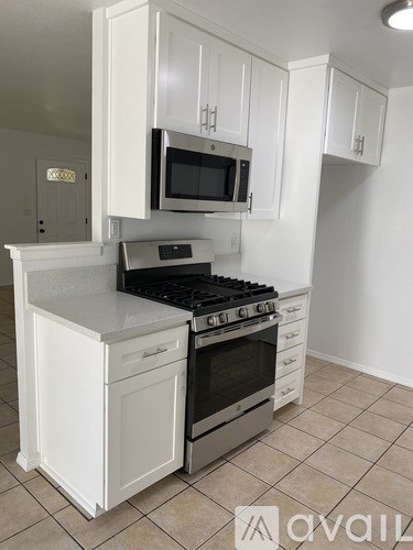 A kitchen with white cabinets and a black stove top.