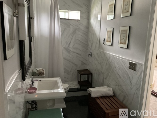 A bathroom with a marble wall and a wooden bench.