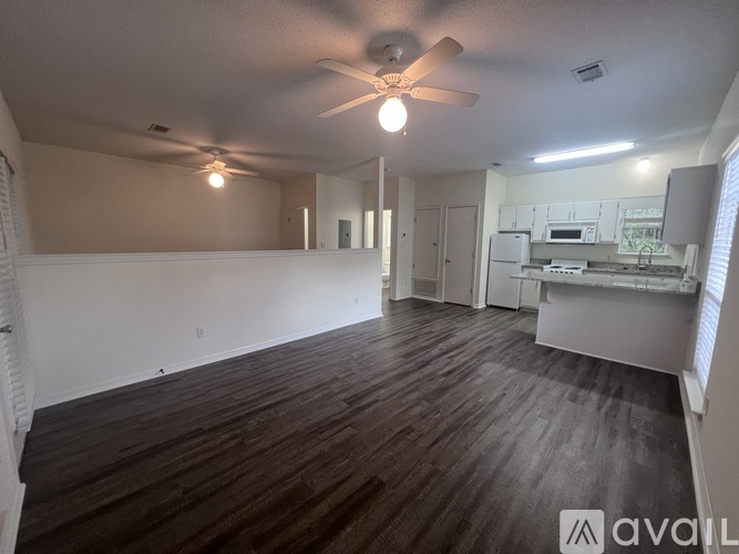 A spacious room with a ceiling fan and wooden flooring.