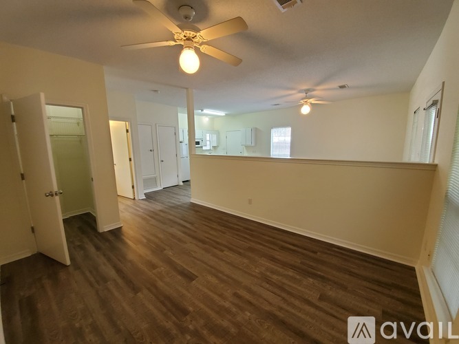 A room with a ceiling fan and wooden flooring.