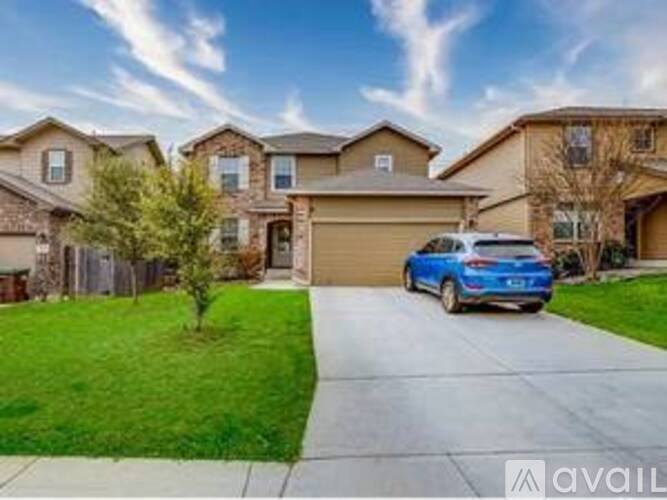 A blue car is parked in front of a house with a driveway.