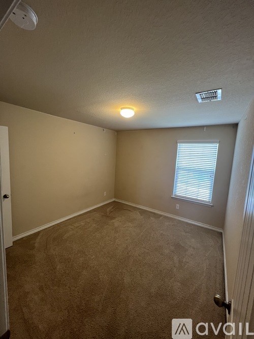A room with beige carpet and a window with blinds.