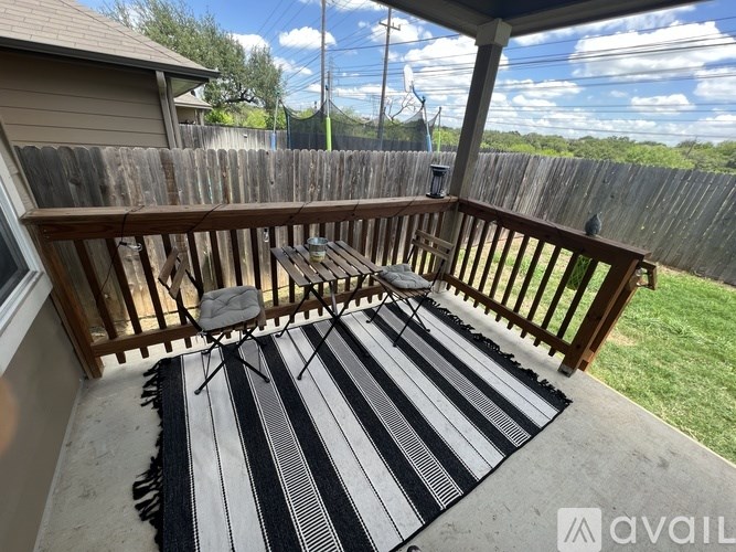 A wooden deck with a striped rug and a chair.