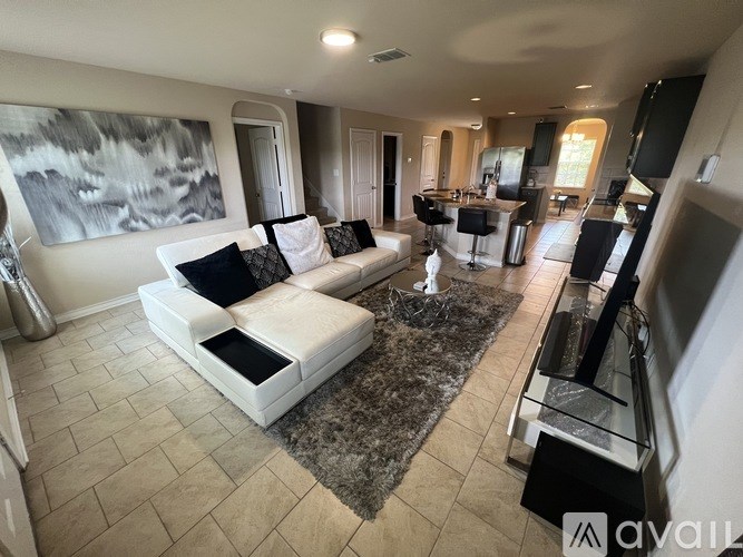 A modern living room with a large white sofa and a grey rug.