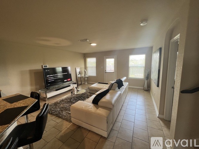 A living room with a black television and white sofa.